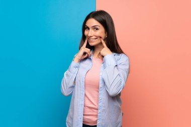 Pembe ve mavi duvar mutlu ve keyifli bir ifadeyle gülümseyen genç kadın