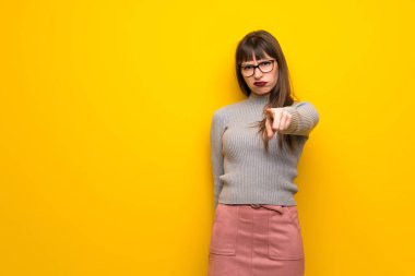 Cepheye dönük ve hayal kırıklığına uğramış sarı duvarın üzerinden gözlüklü kadın