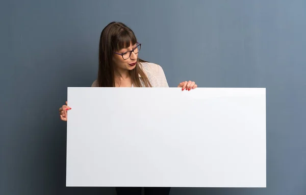 Žena Brýlemi Nad Modré Zdi Drží Prázdná Bílá Transparent — Stock fotografie