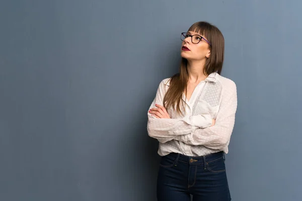 Mujer Con Gafas Sobre Pared Azul Mirando Hacia Arriba Con — Foto de Stock