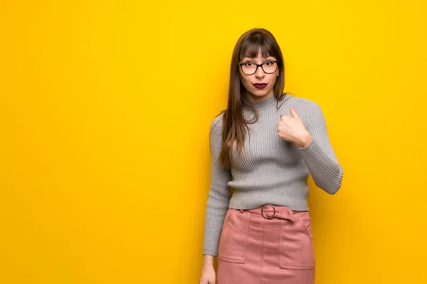 驚きの表情で黄色の壁で眼鏡を持つ女性 — ストック写真