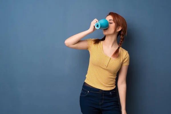 Joven Pelirroja Sobre Fondo Azul Sosteniendo Una Taza Café Caliente —  Fotos de Stock