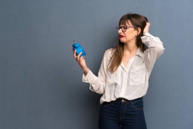 Mavi duvarın geç ve tutan vintage çalar saat oldu çünkü huzursuz üzerinden gözlüklü kadın