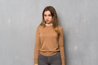 Genç kız üzgün ve depresyonda ifade ile dokulu duvar üzerinde