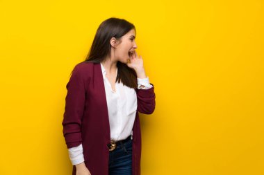 Genç kadın için lateral açık ağızlı bağırmayı sarı duvarın üzerinden
