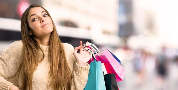 Chica Joven Con Bolsas Compras Haciendo Gestos Dudas Mientras Levanta — Foto de Stock