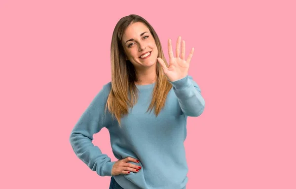 青いシャツ 分離ピンク背景に指で数えるとブロンドの女性 — ストック写真