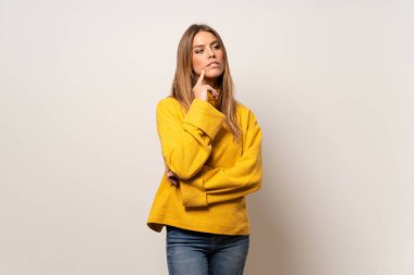 Kadın sarı kazaklı bir fikir ararken süre düşünme izole duvarın üzerinden