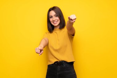 Süre gülümseyen genç kadın sarı duvarın üzerinden parmak seni işaret