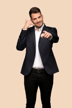 Telefon jest yapma ve açık koyu sarı arka plan üzerinde işaret yakışıklı iş adamı