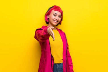 İyi bir anlaşma kapanış için el sıkışan sarı duvarın üzerinden pembe saçlı genç kadın