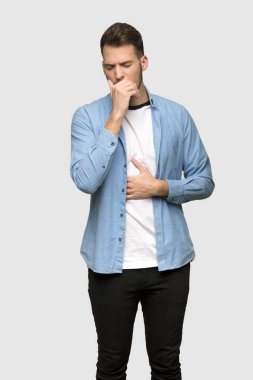 Yakışıklı adam öksürük ile acı ve gri arka plan üzerinde kötü hissediyor