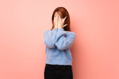 Gözleri eller tarafından kapsayan ve parmaklarının arasından seyir pembe genç Kızıl saçlı kadın