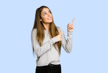 işaret parmağı ile işaret ve üzerinde mavi arka plan bakmak genç kız