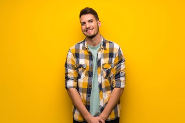 Sarı duvar mutlu ve gülümseyen yakışıklı adam