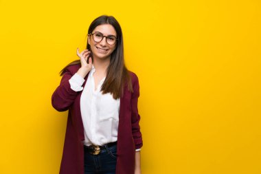 Sarı duvar ile gözlük ve gülümseyen genç kadın