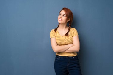 Mavi arka planı süre gülümseyen ararken genç Kızıl saçlı kadın