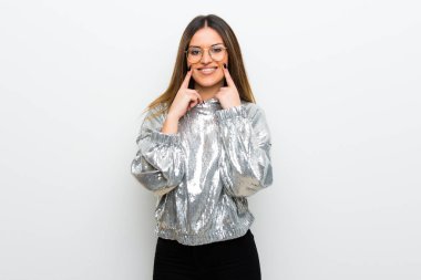 Mutlu ve keyifli bir ifadeyle gülümseyen beyaz duvarın üzerinden gözlüklü genç kadın