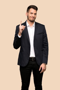 Gösterilen ve koyu sarı arka plan üzerinde en iyi iz içinde parmak kaldırma yakışıklı iş adamı