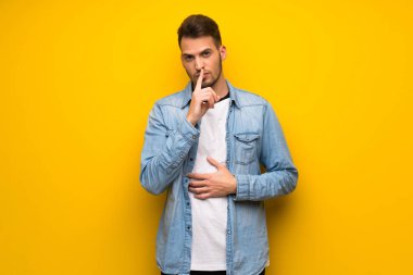 Yakışıklı bir işaret parmağını ağzına koyarak sessizlik jest gösteren sarı duvarın üzerinden