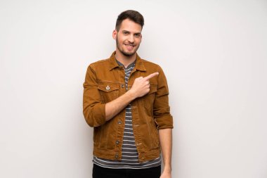 Beyaz duvar tarafına işaret eden bir ürün sunmak için yakışıklı adam