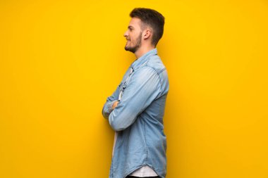 Lateral pozisyonda sarı duvarın üzerinden yakışıklı adam