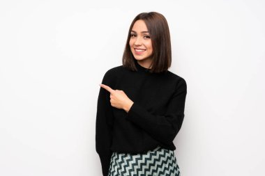 Beyaz duvar tarafına işaret eden bir ürün sunmak için genç kadın