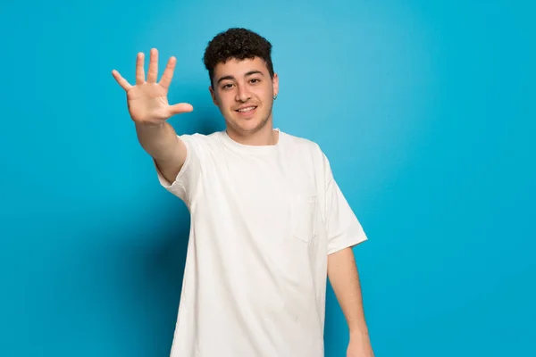 Mladý Muž Nad Modrým Pozadím Počítání Pět Prstů — Stock fotografie