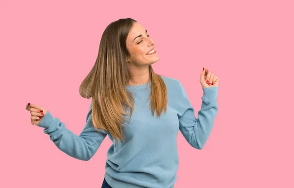 青いシャツに金髪の女性が分離 ピンクの背景のパーティーで音楽を聴きながら踊りを楽しむ — ストック写真