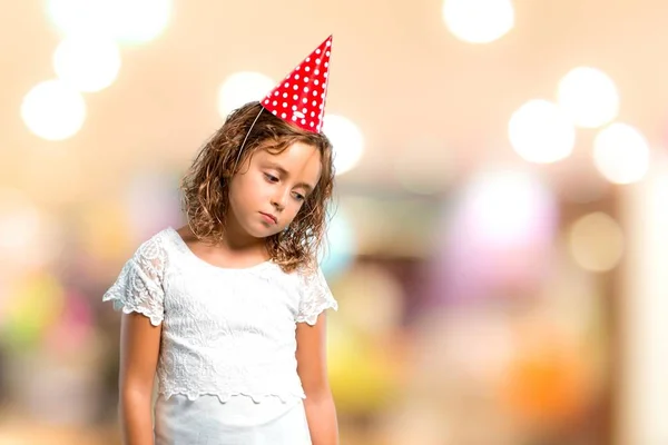 Menina em uma festa de aniversário segurando um saco de presente infeliz e frustrado com algo. Expressão facial negativa em fundo desfocado — Fotografia de Stock