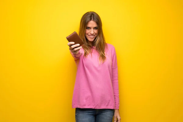 Vrouw Met Roze Trui Gele Muur Houdt Een Portefeuille — Stockfoto