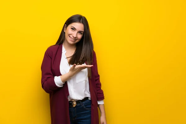 Ung Kvinna Över Gul Vägg Presenterar Idé Medan Ser Leende — Stockfoto