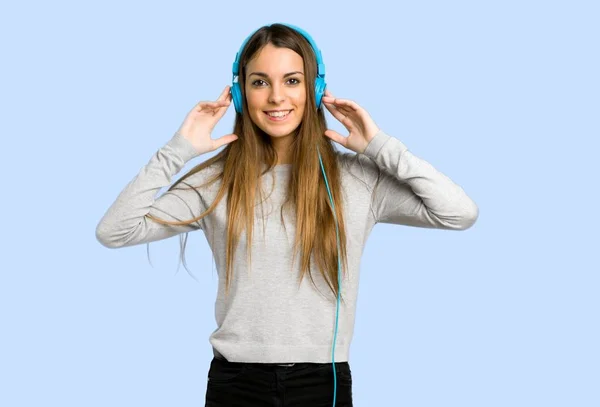 Junges Mädchen Hört Musik Mit Kopfhörern Auf Blauem Hintergrund — Stockfoto