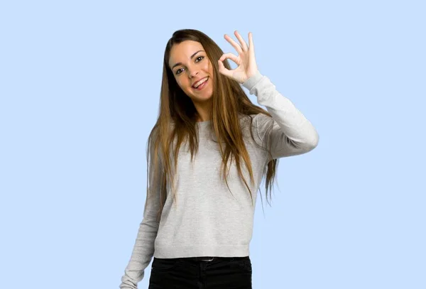 Молода Дівчина Показує Знак Пальцями Синьому Фоні — стокове фото