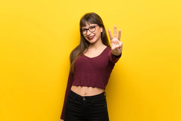 指で黄色の壁幸せとカウント で眼鏡を持つ女性 — ストック写真