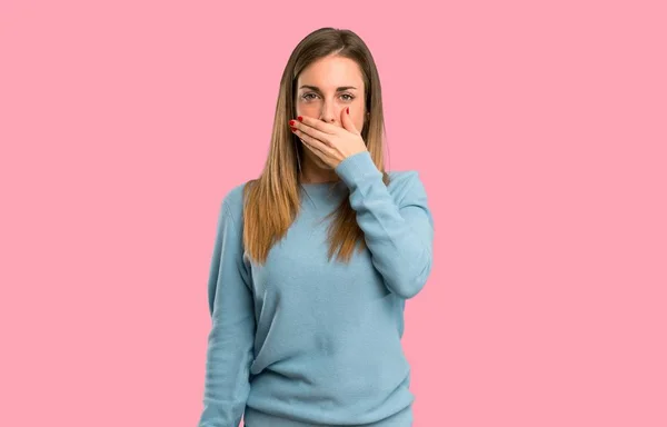 分離のピンクの背景に不適切な何かを言うための手で口を覆っている青いシャツとブロンドの女性 — ストック写真