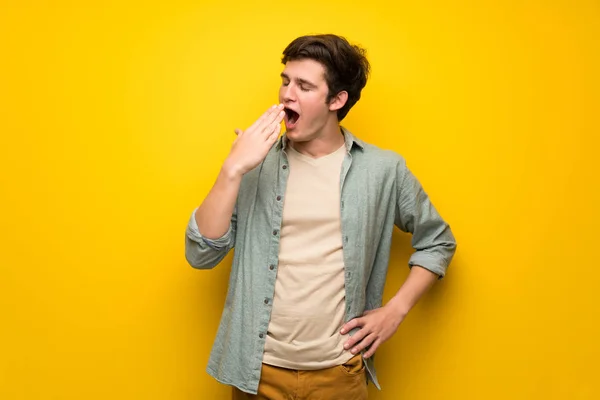 Adolescente Uomo Sopra Parete Gialla Sbadigliando Coprendo Bocca Spalancata Con — Foto Stock