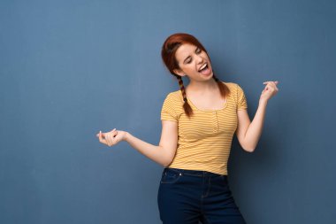 Mavi arka plan genç Kızıl saçlı kadın zevk müzik bir partide dans