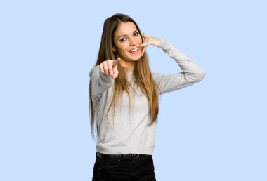 telefon jest yapma ve açık mavi zemin üzerine işaret eden genç kız