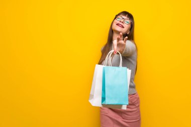 Bir sürü alışveriş torbaları tutan sarı duvarın üzerinden gözlüklü kadın