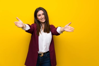 Sunulması ve el ile gelmek davet sarı duvarın üzerinden genç kadın