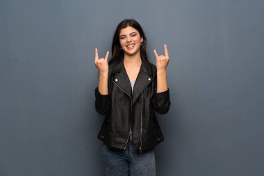 Genç kız üzerinde gri duvar rock jest yapma