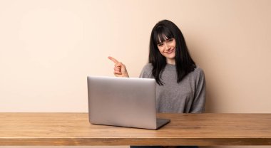 Ürün sunmak için tarafına işaret onu laptop ile çalışan genç kadın