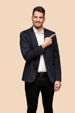 Koyu sarı arka plan üzerinde bir ürün sunmak için yakışıklı iş adamı tarafına işaret