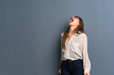 Ağız açık ile ön bağırarak mavi duvarın üzerinden gözlüklü kadın