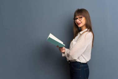 Bir kitap ve okuma zevk mavi duvarın üzerinden gözlüklü kadın
