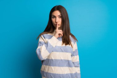 Mavi duvar bir işaret parmağını ağzına koyarak sessizlik jest gösteren genç kadın