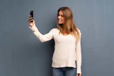 Bir selfie yapma gri arka plan üzerinde sarışın kadın