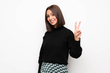 Genç kadın gülümseyerek ve zafer işaret gösteren beyaz duvar yüzünden