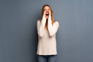 Sarışın kadın bağırıyor ve bir şey ilan gri arka plan üzerinde